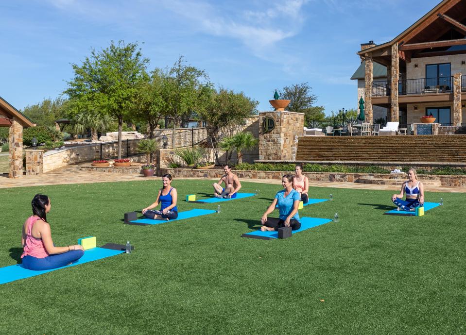 People taking a yoga class outside on a lawn.