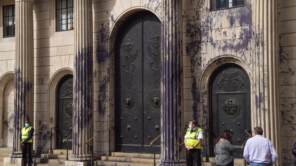 People stand outside the Bank of England covered in fake oil...