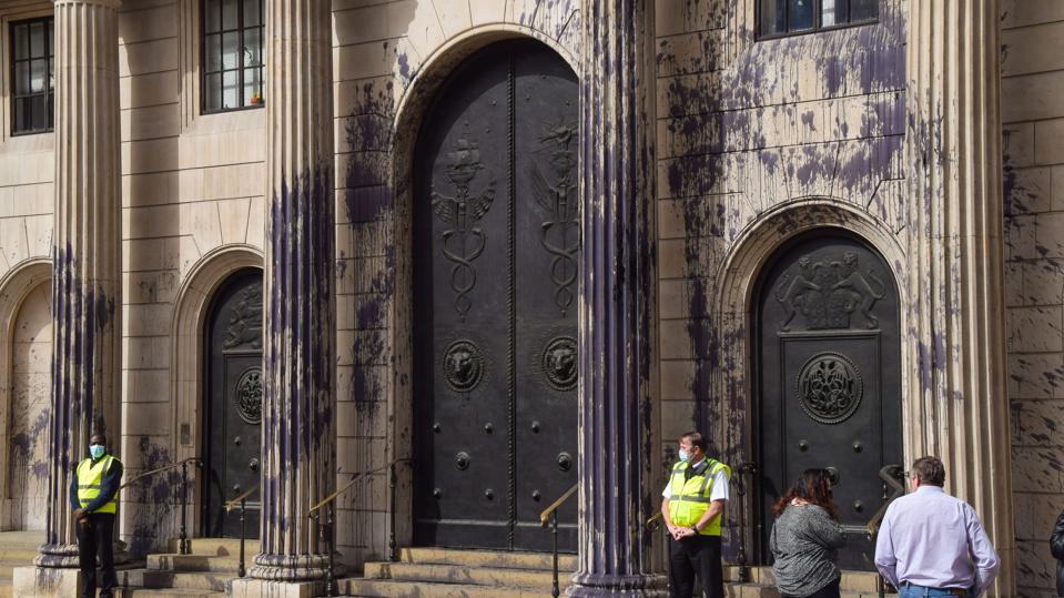 People stand outside the Bank of England covered in fake oil...