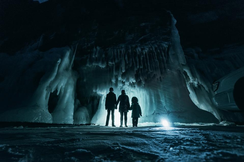 A family of three in a dark, ice filled grotto