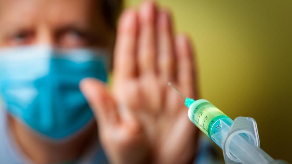 Vaccination syringe approaching in foreground