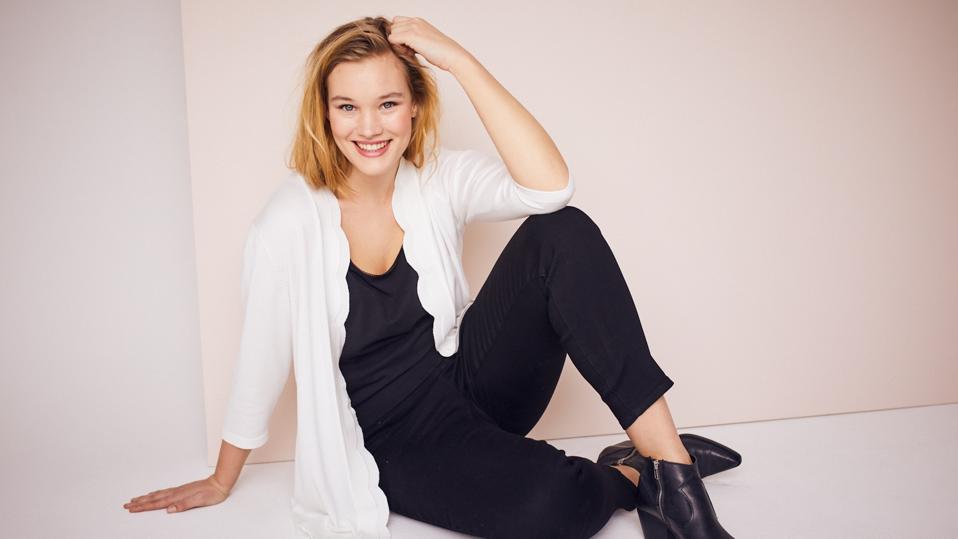 A woman model a white seater, and black shirt and top from Dressbarn.com