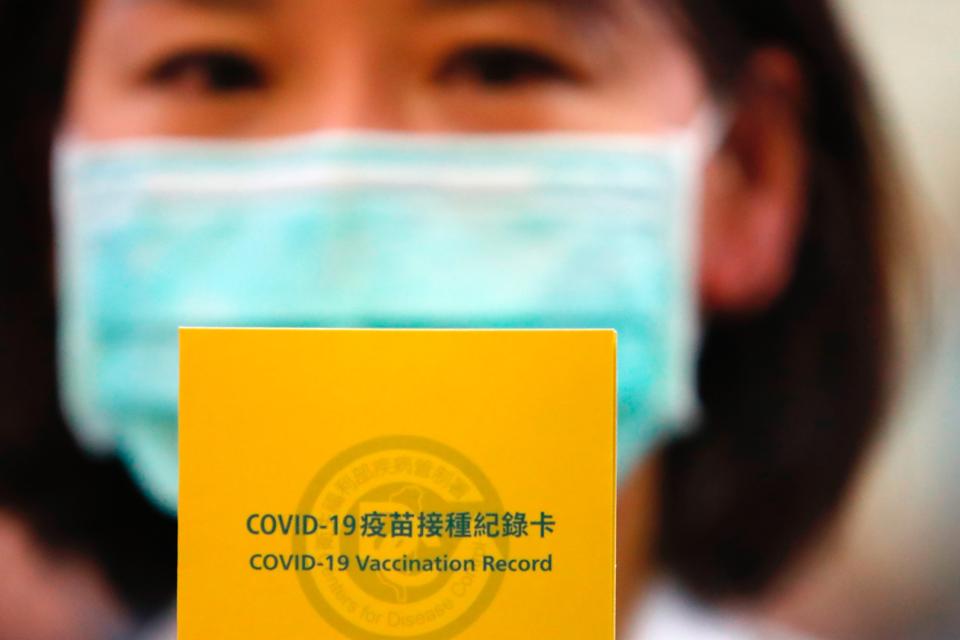 A nurse holds a Covid vaccination record card after she...