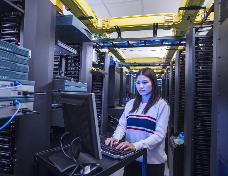 Young woman working on desktop computer in server room