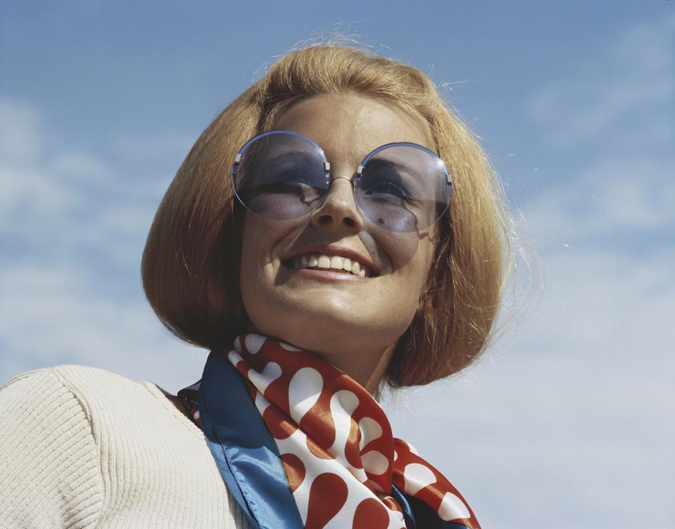 Young woman wearing sunglasses, smiling, close-up