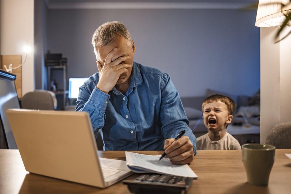 Four Top Stressors When Working Remotely And How To Avoid Them 3 Stressed Man With his two years old son Working From Home