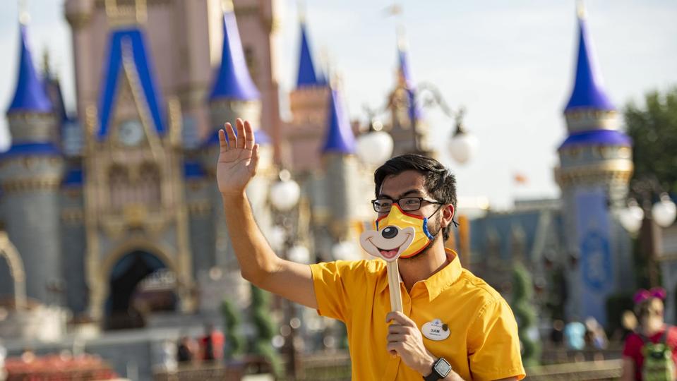 Walt Disney World cast member waves to guests in front of castle