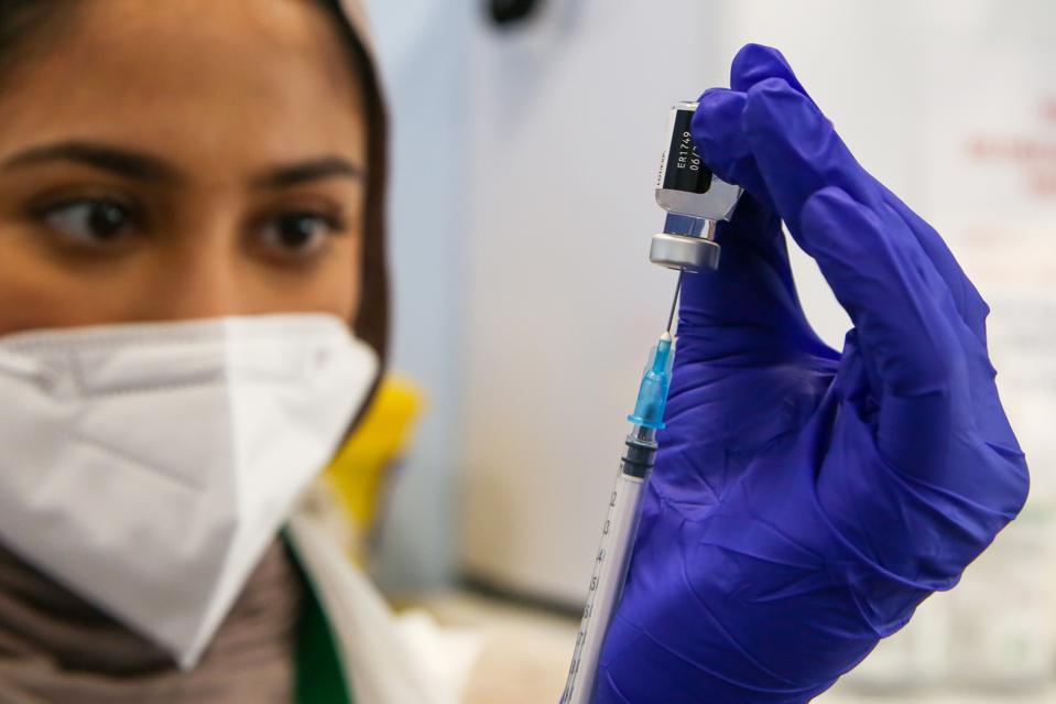 A NHS staff member prepares to administer the Pfizer and...