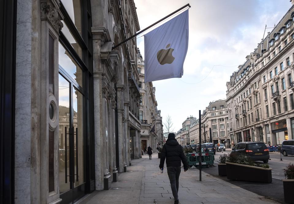 Un uomo passa davanti a negozi Apple a Londra, durante ...