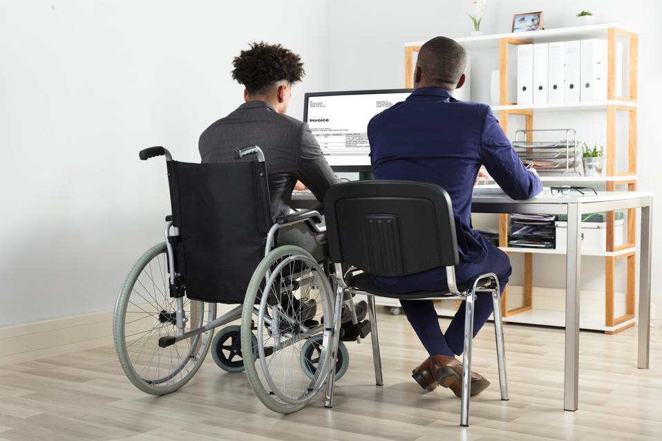Rear View Of Physically Impaired Businessman With His Partner Working On Computer On Desk