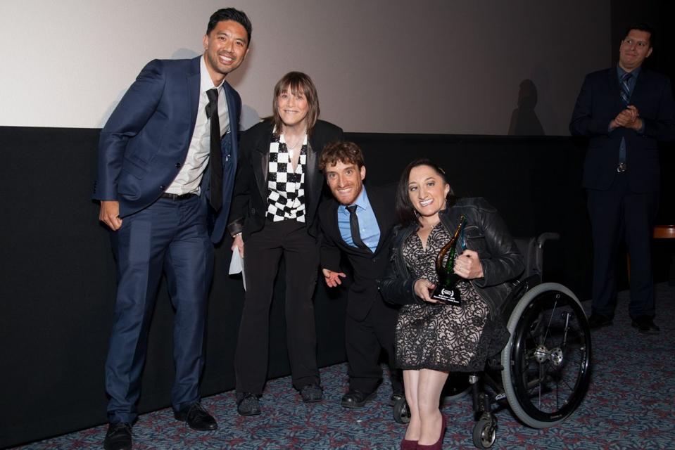 An asian man, white woman, white man who is a small person, & white woman in a wheelchair.