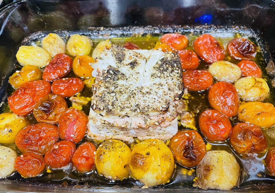 Baked Feta Cheese, roasted tomatoes, garlic, vinegar and spices are shown in a glass baking dish. Once cooked, it becomes a quick and delicious pasta sauce.