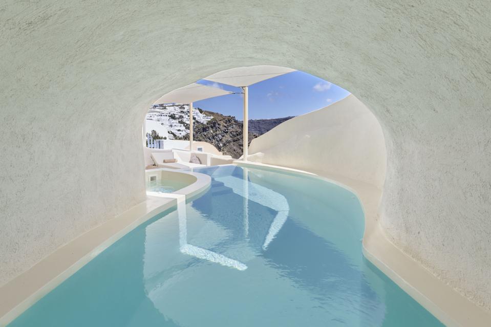 A long swimming pool winds through a tunnel at Mystique resort on Santorini, Greece