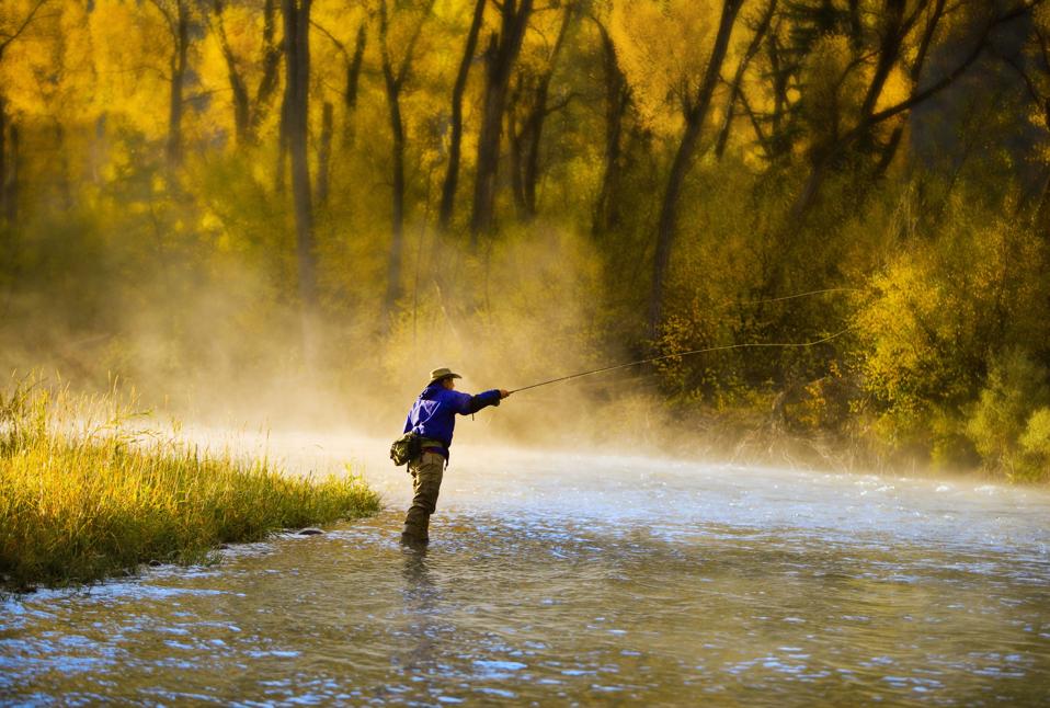 Male fly fisherman casting on the river.