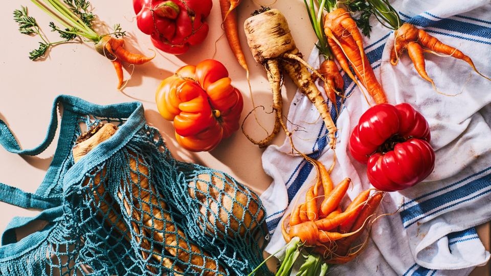 carrots, tomatoes and parsnips in a mesh shopping bag from the farmer's market