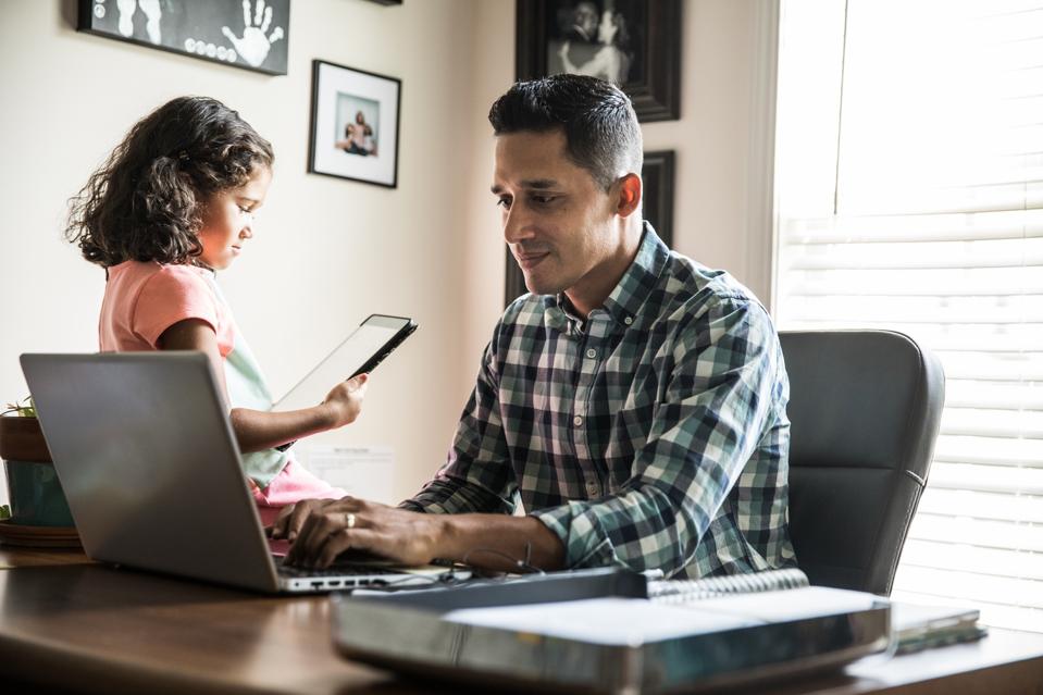 Father working at home with young daughter