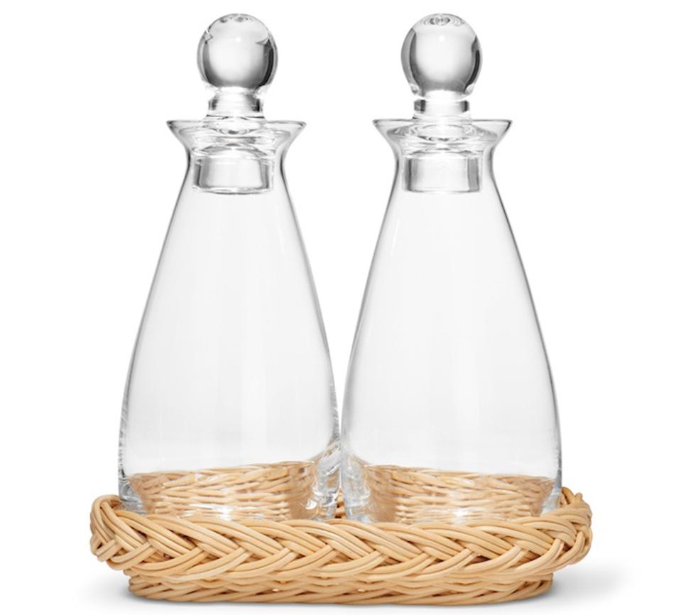 Aerin Freya Wicker Oil and Vinegar Bottle Set. Clear bottles with stoppers in a basket.