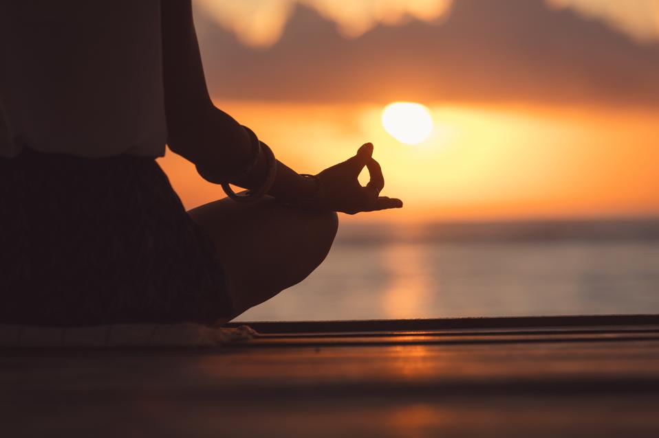 Young woman practicing yoga on the beach.