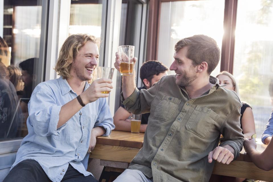 Male friends toasting beer glasses at pub