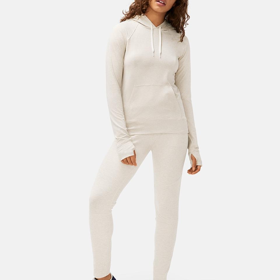 A woman wears an oatmeal All-Day Hoodie from Outdoor Voices.