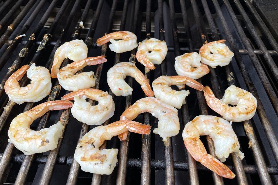Perfectly grilled Colossal shrimp are shown on a stainless-steel grill grate just before they are removed and placed in a tomatillo salsa marinade.