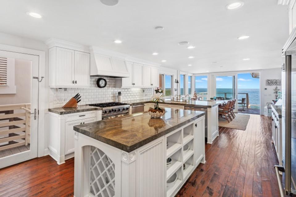 A large, modern white kitchen overlooking the water