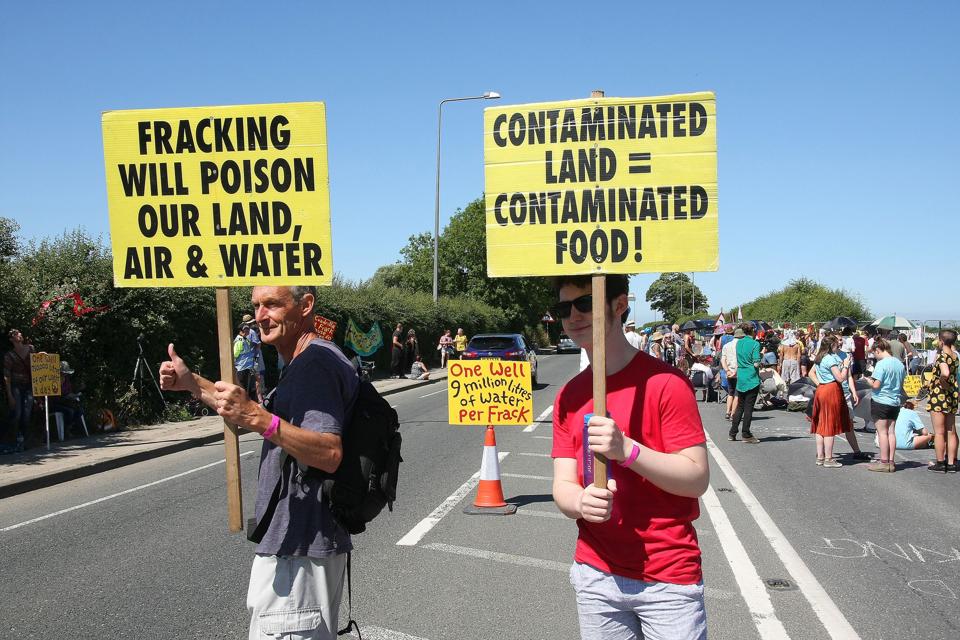 Two local Anti Frack Protesters hold placards on a main road...
