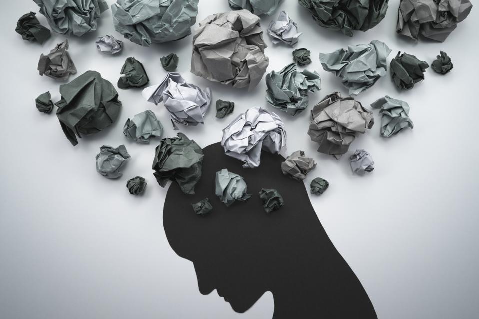 Silhouette of troubled person head, with waste paper bundles to represent thoughts