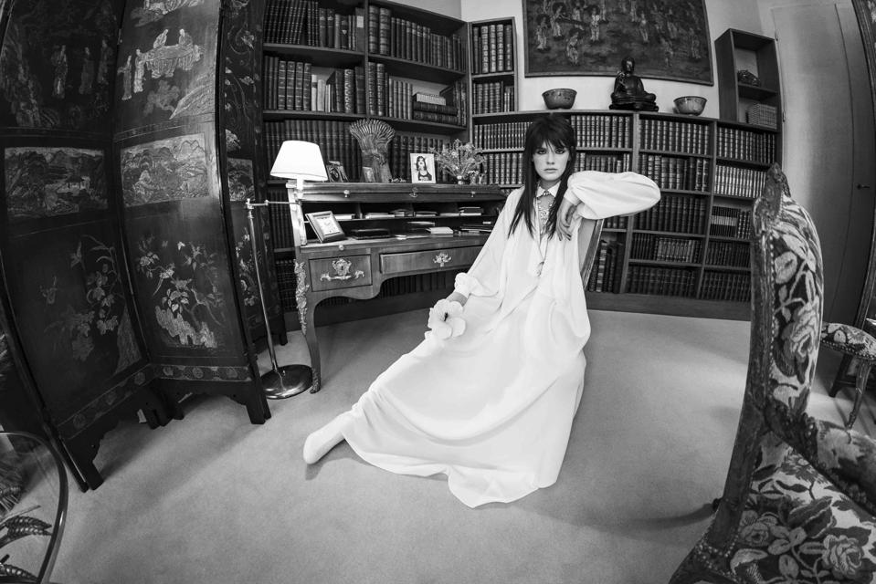 Lola Nicon grasps a white hibiscus bloom, a poetic nod to testament of Orpheus by jean Cocteau posing in the study go Gabrielle Chanel's apartment