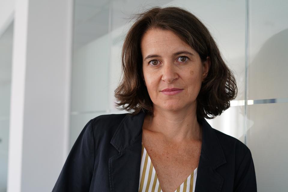 portrait of white woman with shoulder length brown hair, wearing a striped shirt.