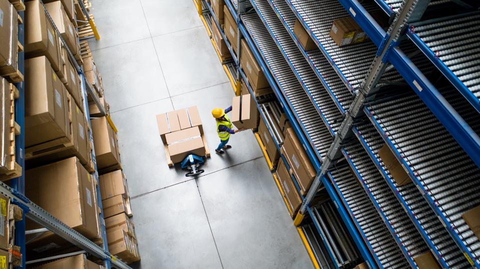 Aerial view of woman worker with face mask working in warehouse.