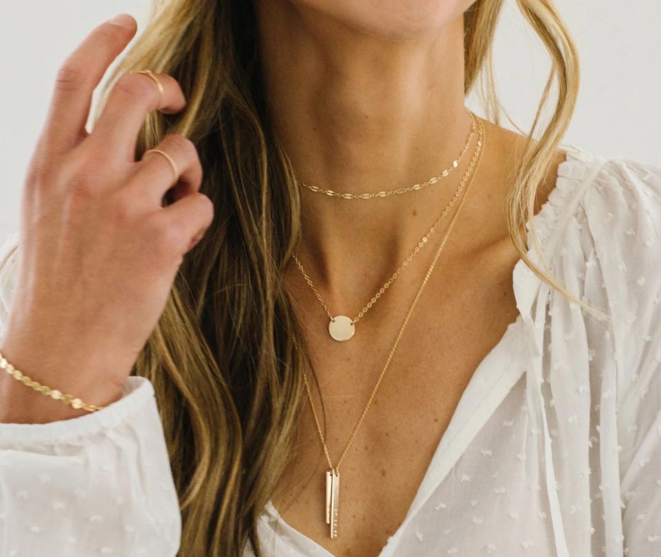 Close up shot of a woman's neck with layered gold necklaces.