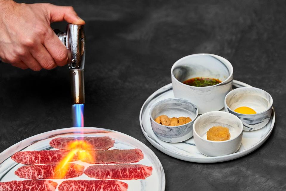 a torch fires up the wagyu before being dressed with uni, egg yolk and soy sauce