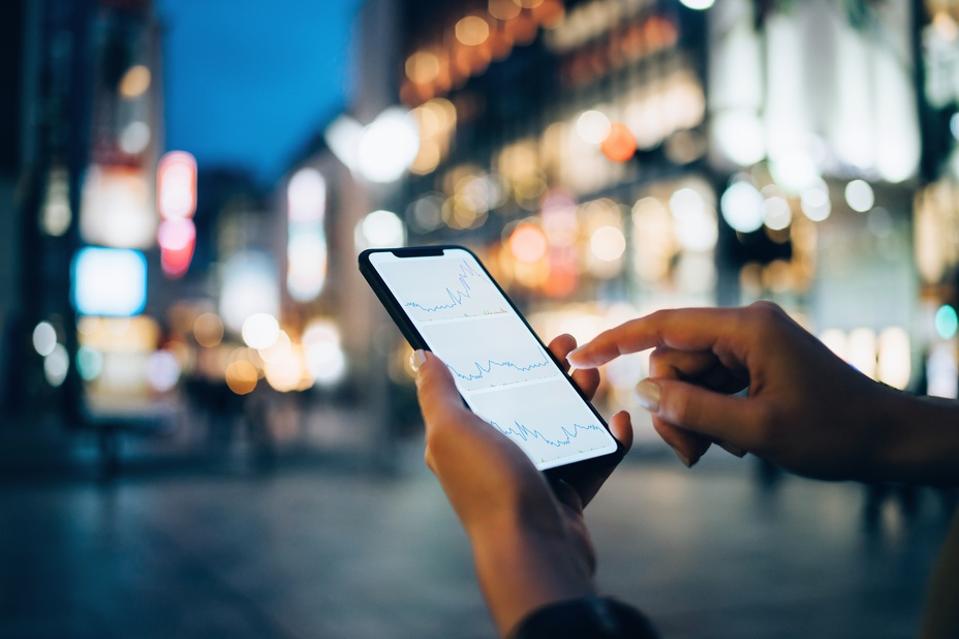 Businesswoman reading financial trading data on smartphone