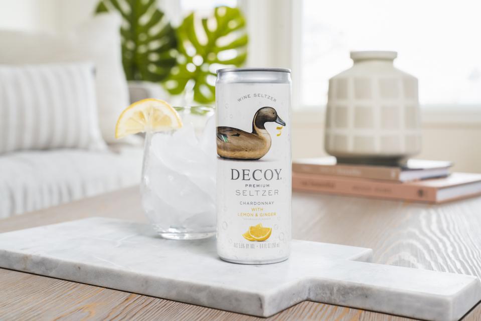 Can of Decoy Chardonnay with Lemon & Ginger wine seltzer on table next to ice-filled glass