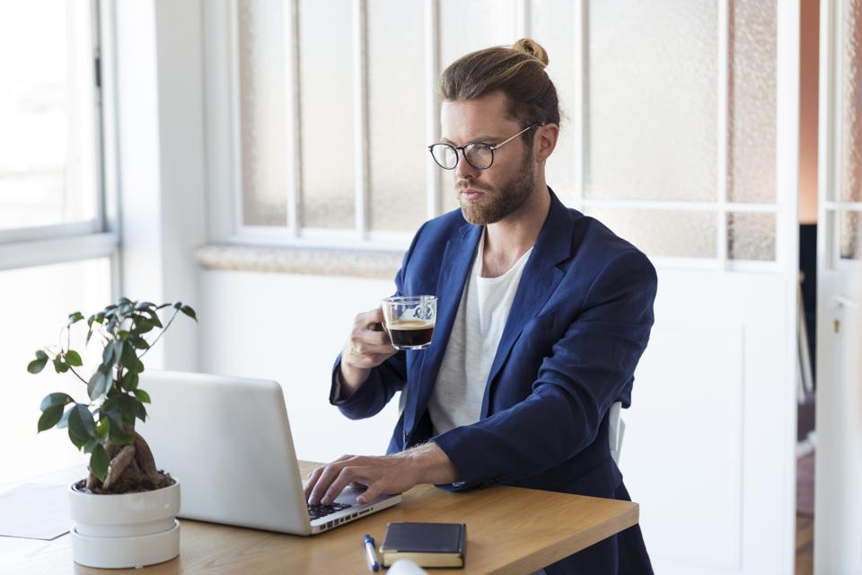 Businessman with laptop and cup of coffee at table
