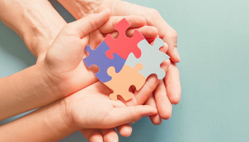 Adult and chiild hands holding jigsaw puzzle shape, Autism awareness, Autism spectrum family support concept, World Autism Awareness Day
