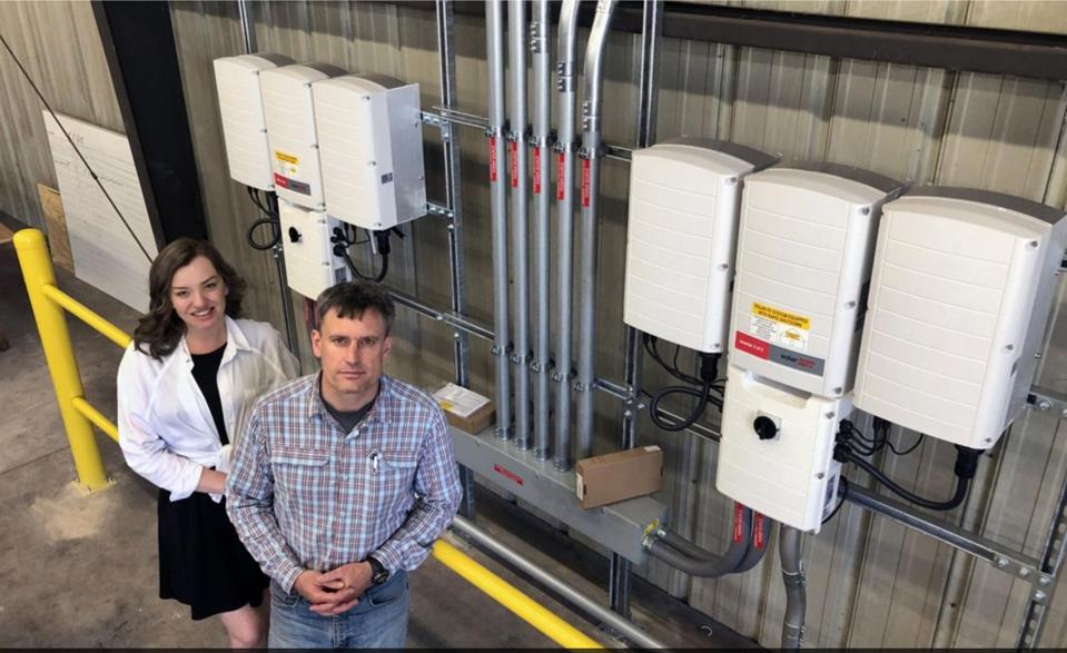 The co-founders of Revolt Energy stand proudly in front of one of their solar panels in West Virginia. 