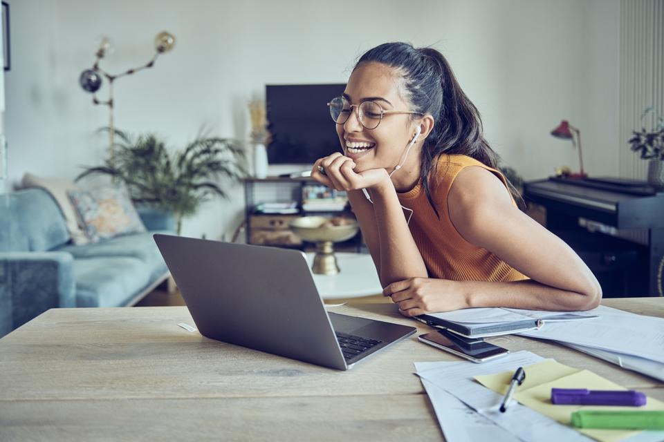 Beautiful young woman working at home with laptop and documents