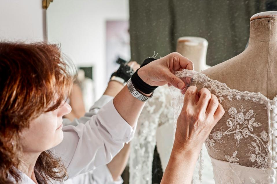 Couturière et brodeuse travaillant dans l'atelier de Cinzia Ferri sur une robe de mariée personnalisée