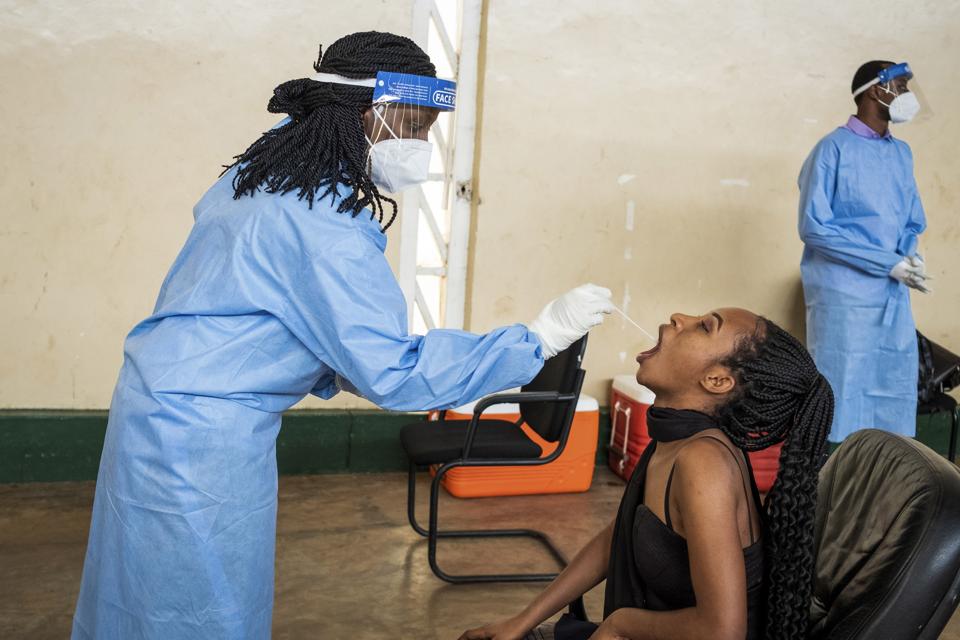 Rwandan Ruth Irumva is given a Covid-19 swab test by a blue-clad health worker.