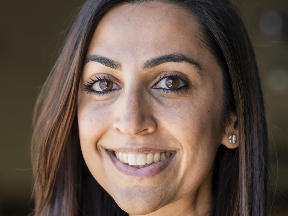 Headshot of Sharma with long brown hair.