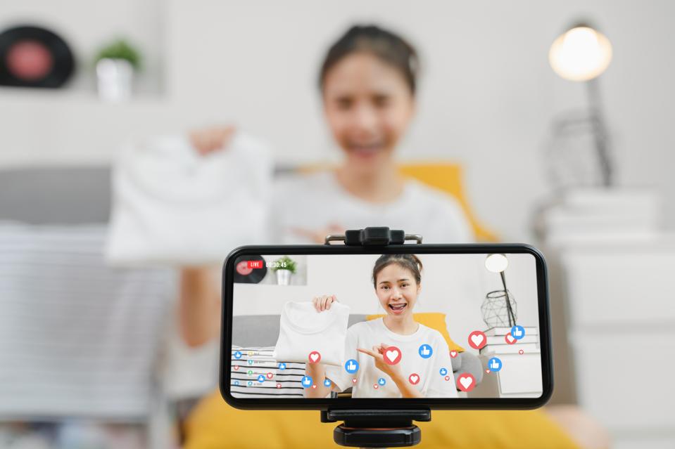 Young Asian women showing clothes and sale online on social with smartphone to customers from home. Network technology concept.