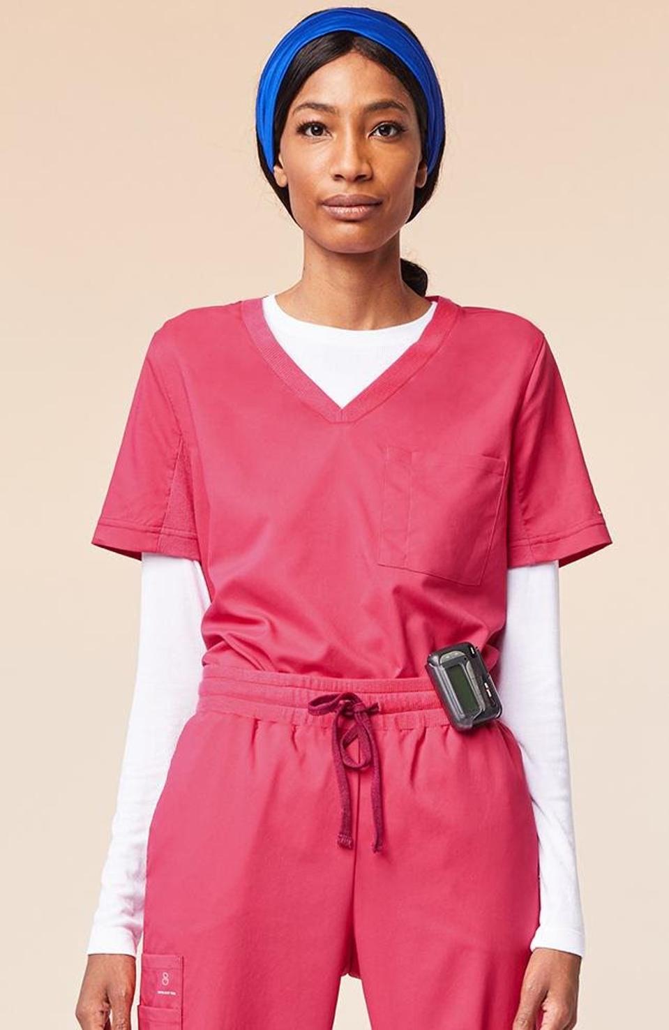 A Black woman wearing red scrubs and a blue headband.