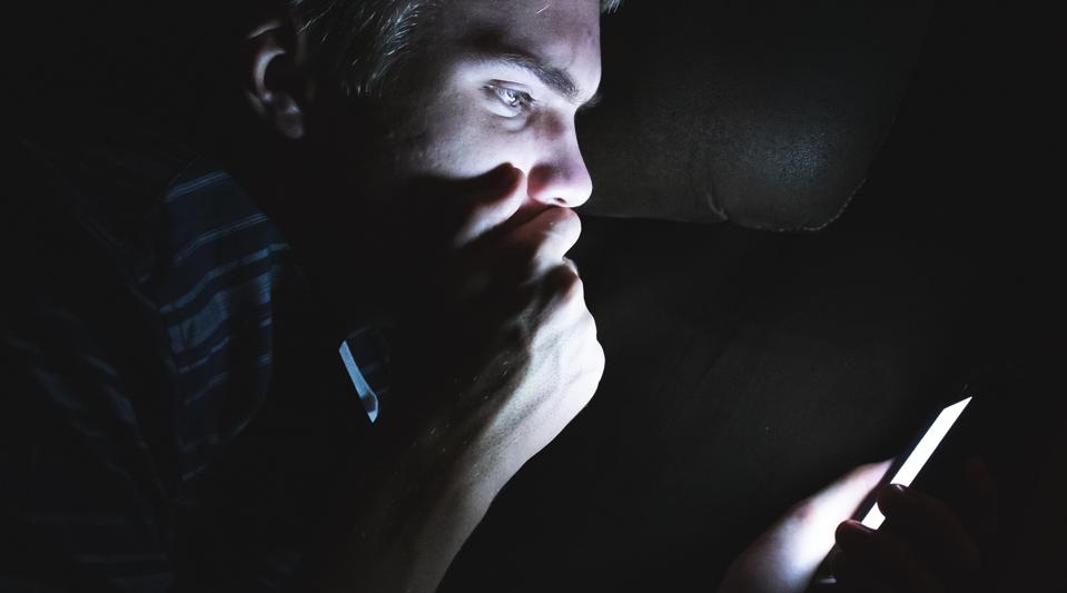 Man on his cellphone in the dark.