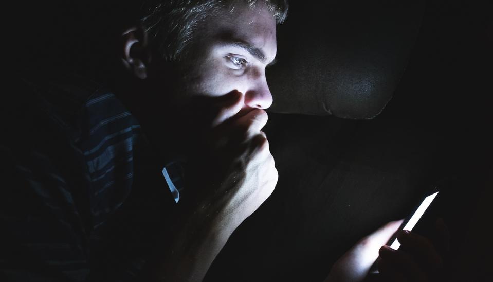 Shocked man on his cellphone in the dark.