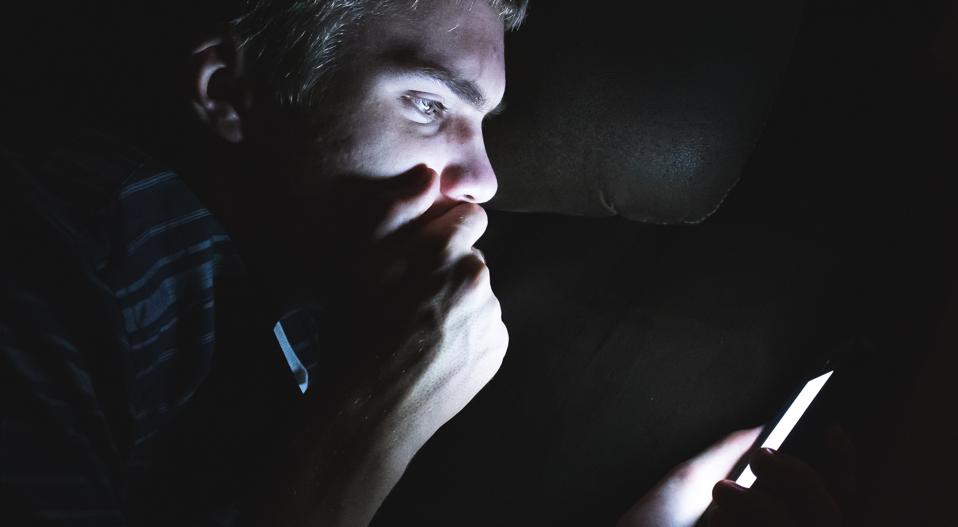 Shocked man on his cellphone in the dark.