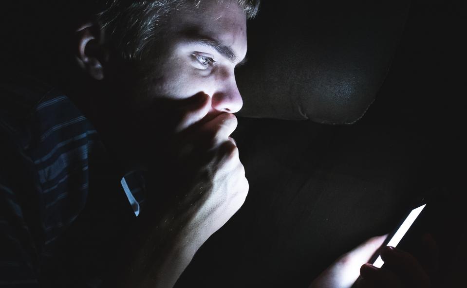 Shocked man on his cellphone in the dark.