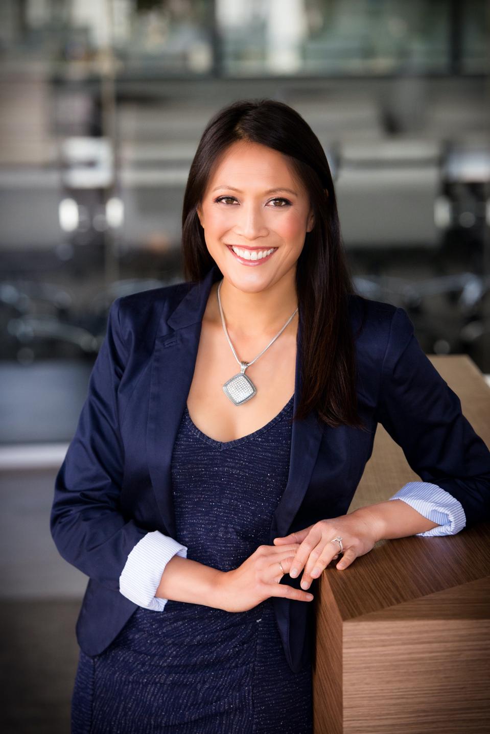 Asian American woman in a navy suit, smiling