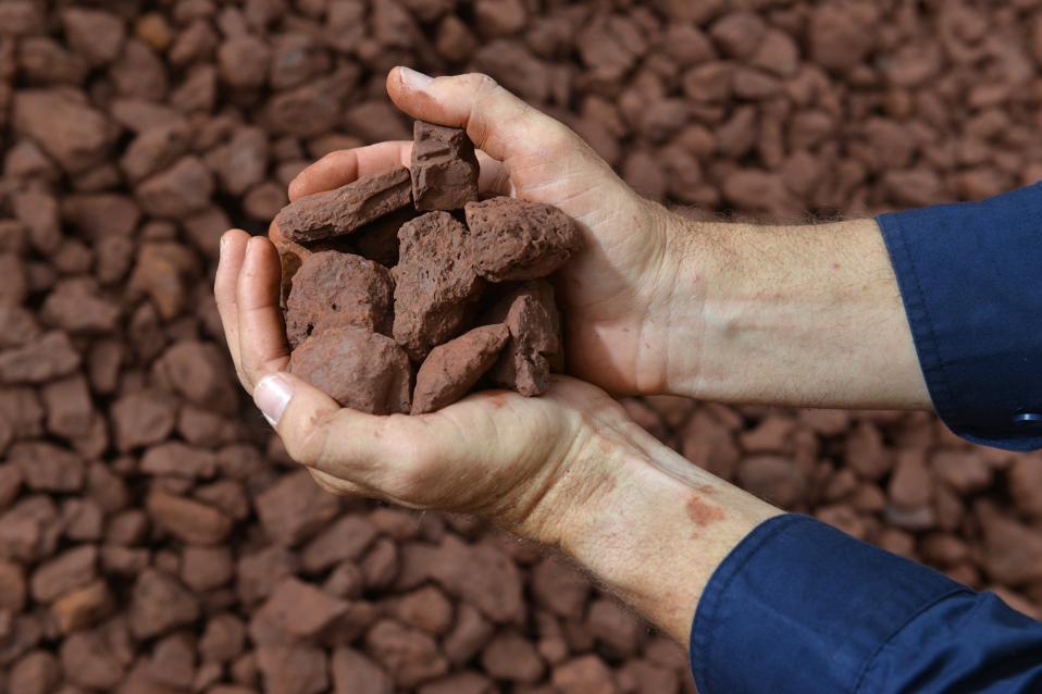 Two hands holding an iron ore sample.